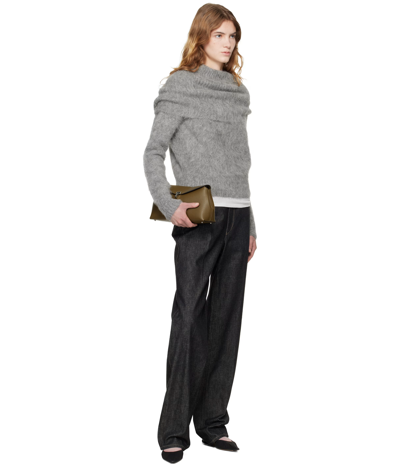 Woman wearing a gray sweater and black pants holding a green clutch on a white background
