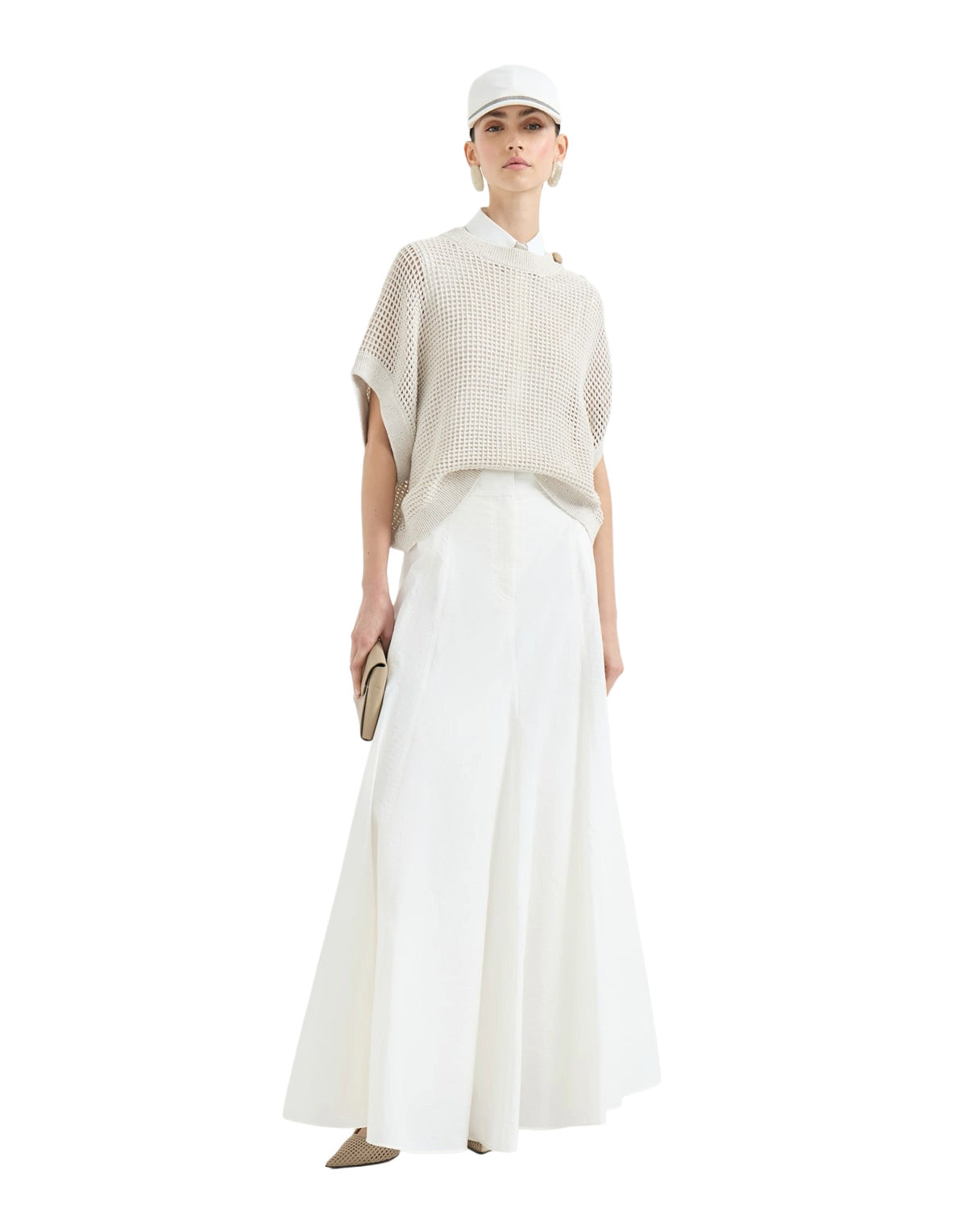 Woman wearing a beige knit top and white pants on a white background