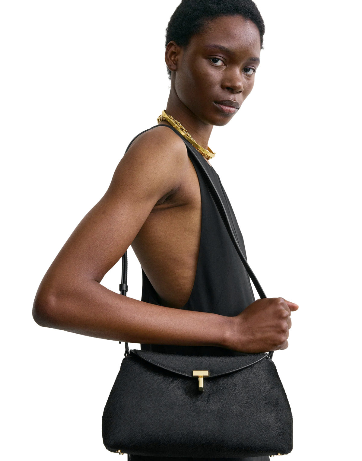 Woman holding a black handbag with a gold clasp on a white background