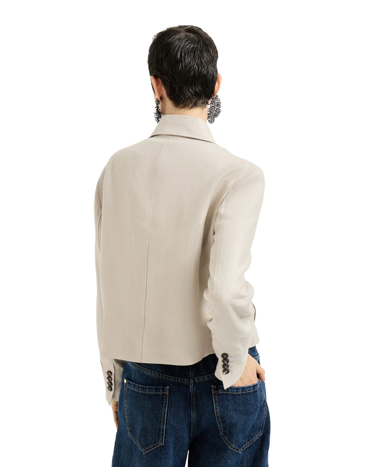 Person wearing a beige jacket and blue jeans on a white background