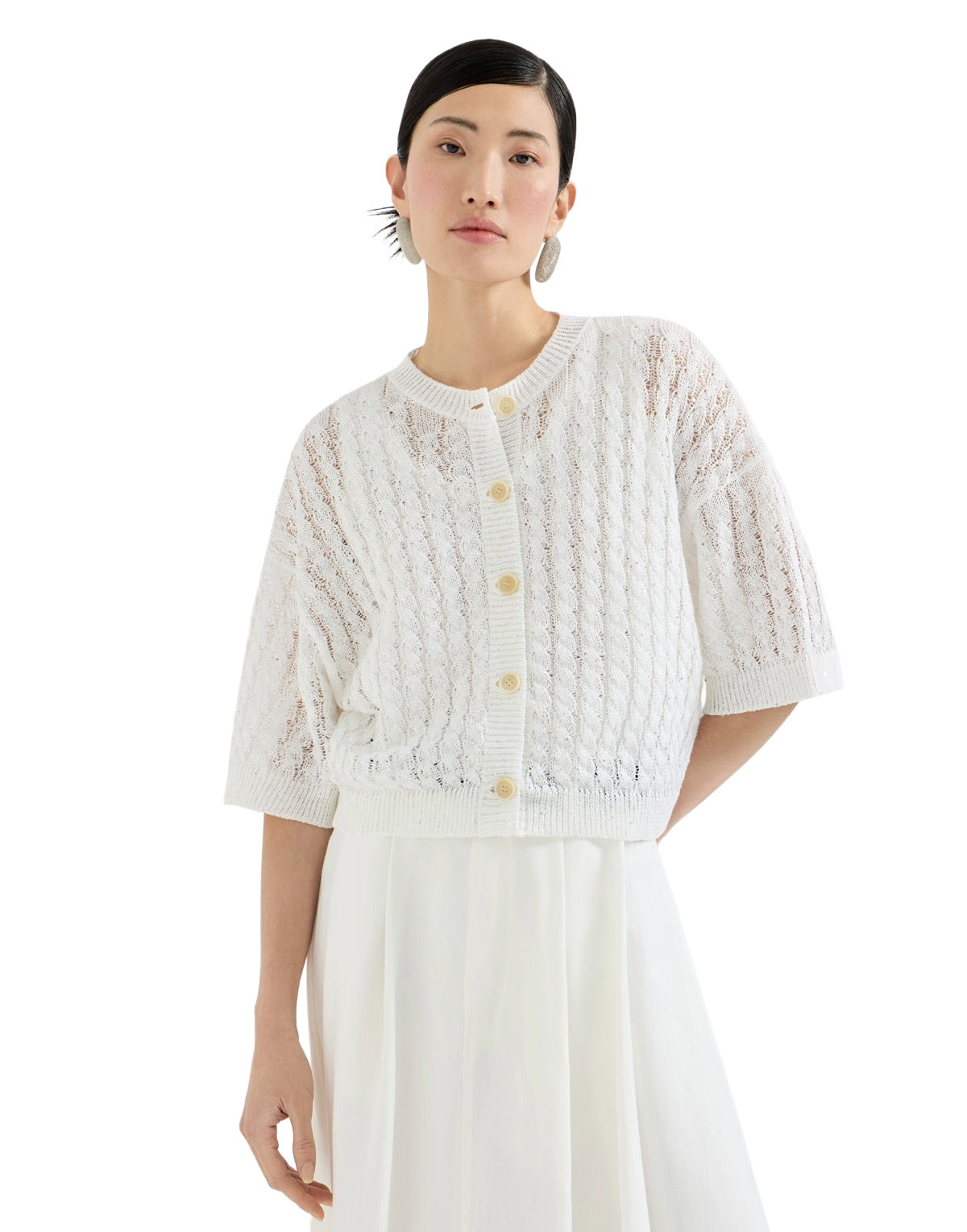 Woman wearing a white lace cardigan with buttons on a white background