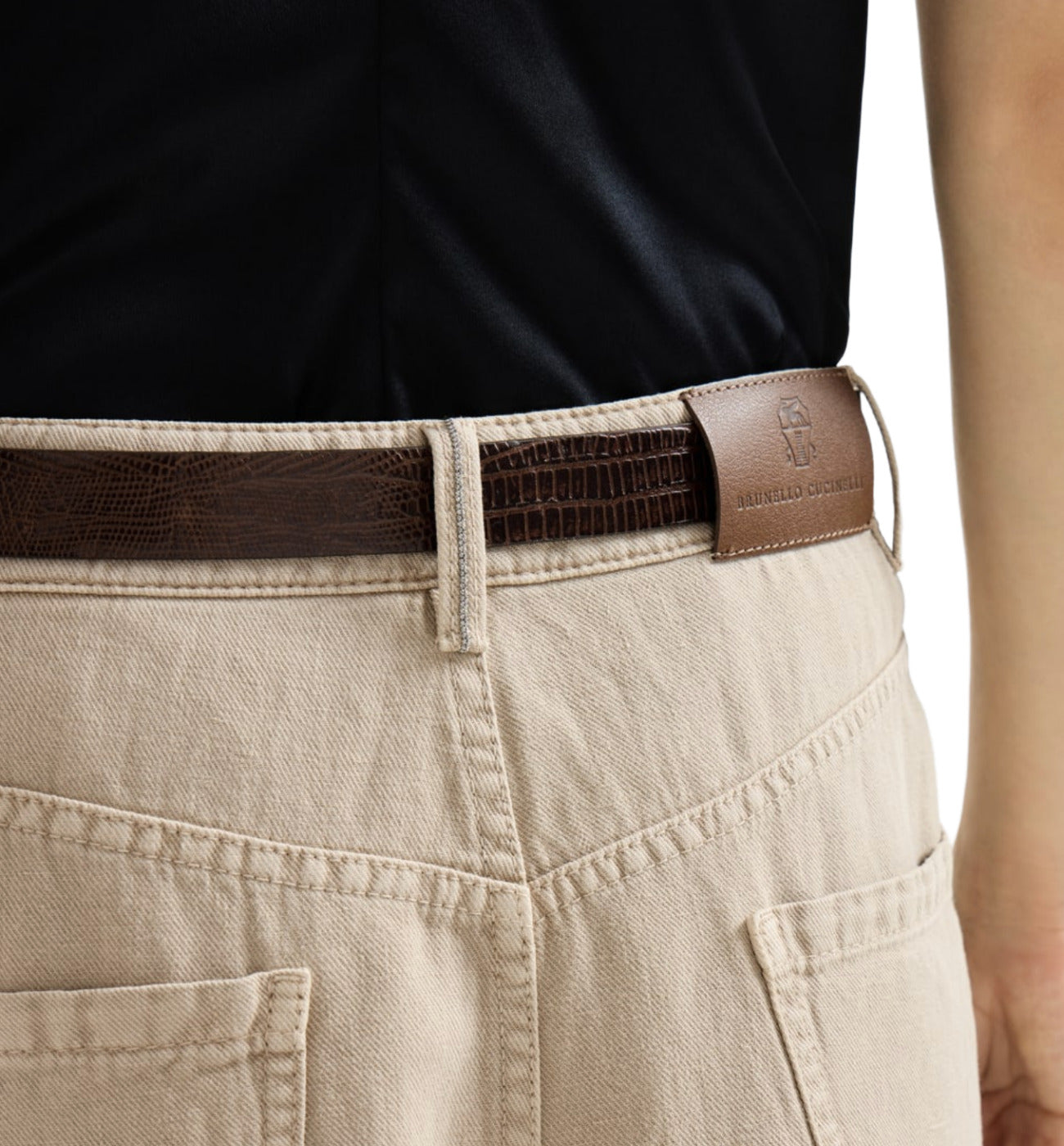 Brown belt with a brand logo worn by a person wearing beige pants.