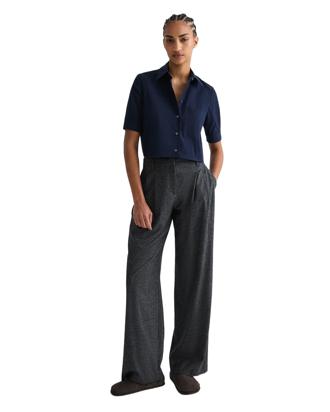 Person wearing a navy shirt and gray pants on a white background