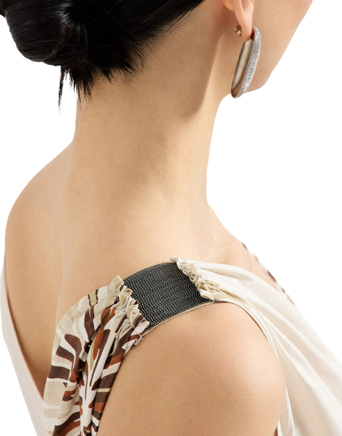 Close-up of a woman wearing a floral top with a black strap over her shoulder on a white background