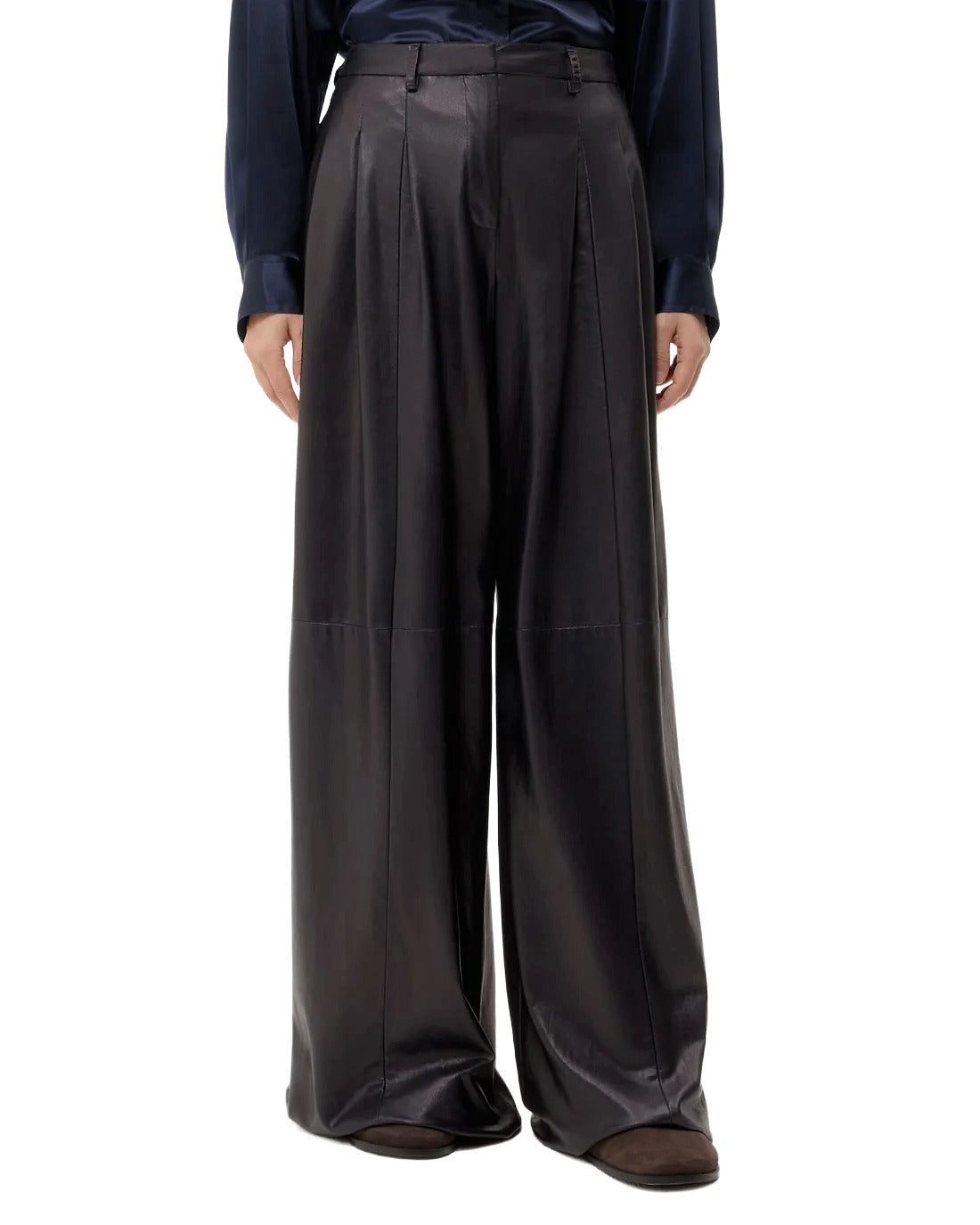 Person wearing dark leather wide-leg pants on a white background