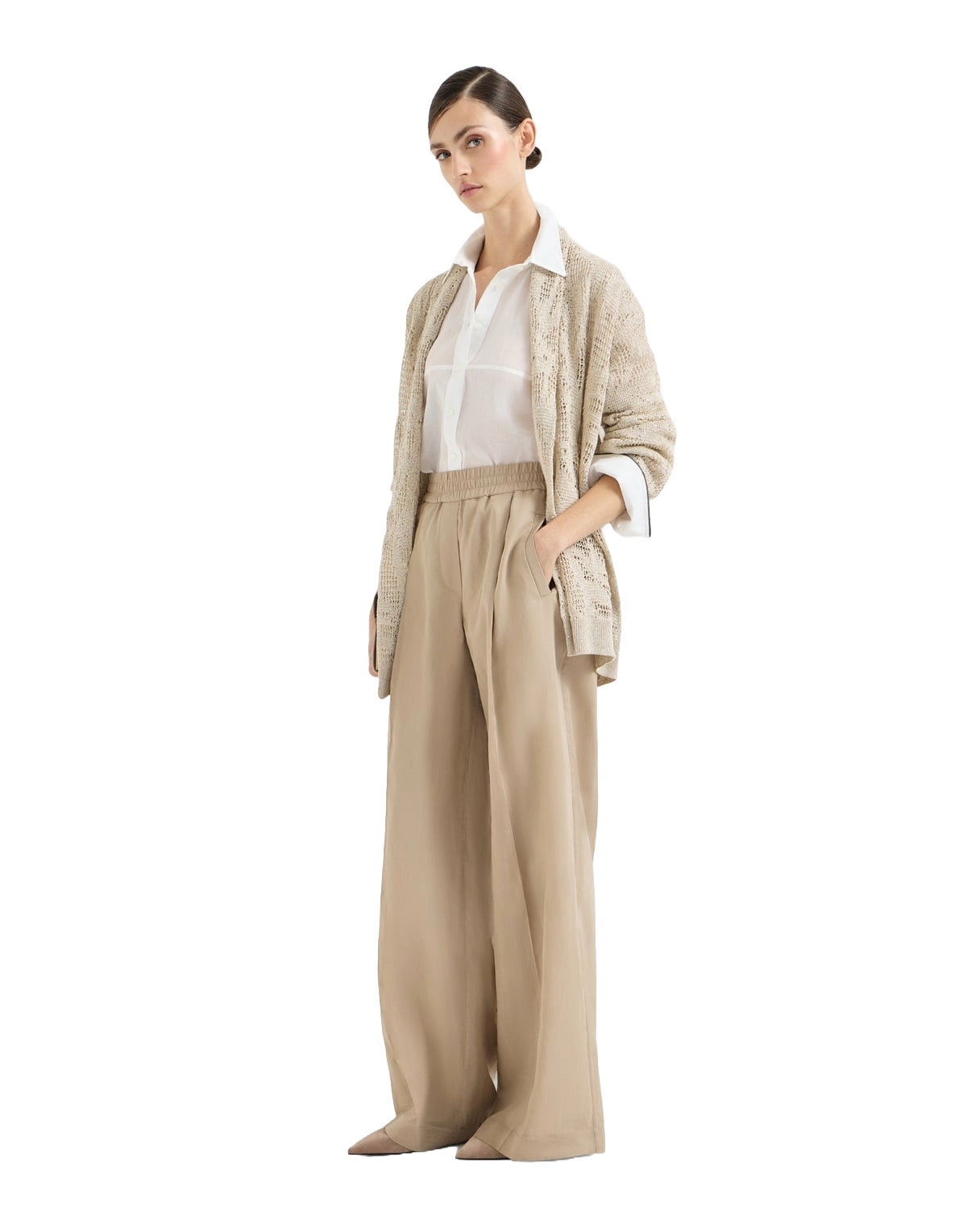 Woman wearing a beige cardigan, white shirt, and beige pants on a white background