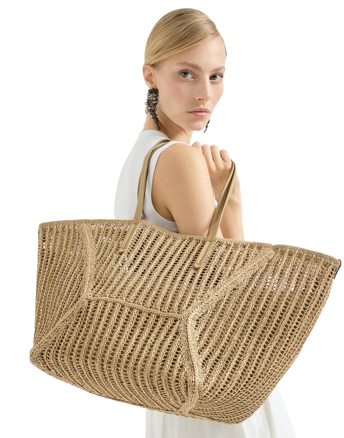Woman holding a large woven beige bag against a white background