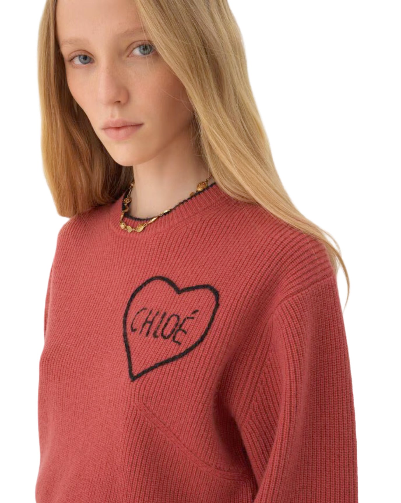 Person wearing a red sweater with a black heart design and 'CHLOé' branding.