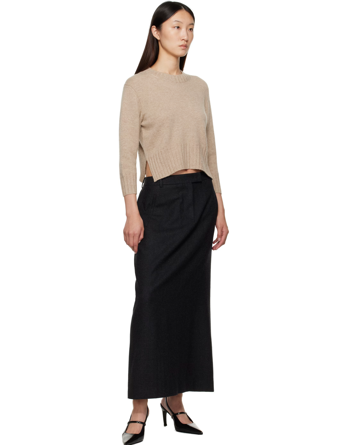 Woman wearing a beige sweater and black skirt on a white background