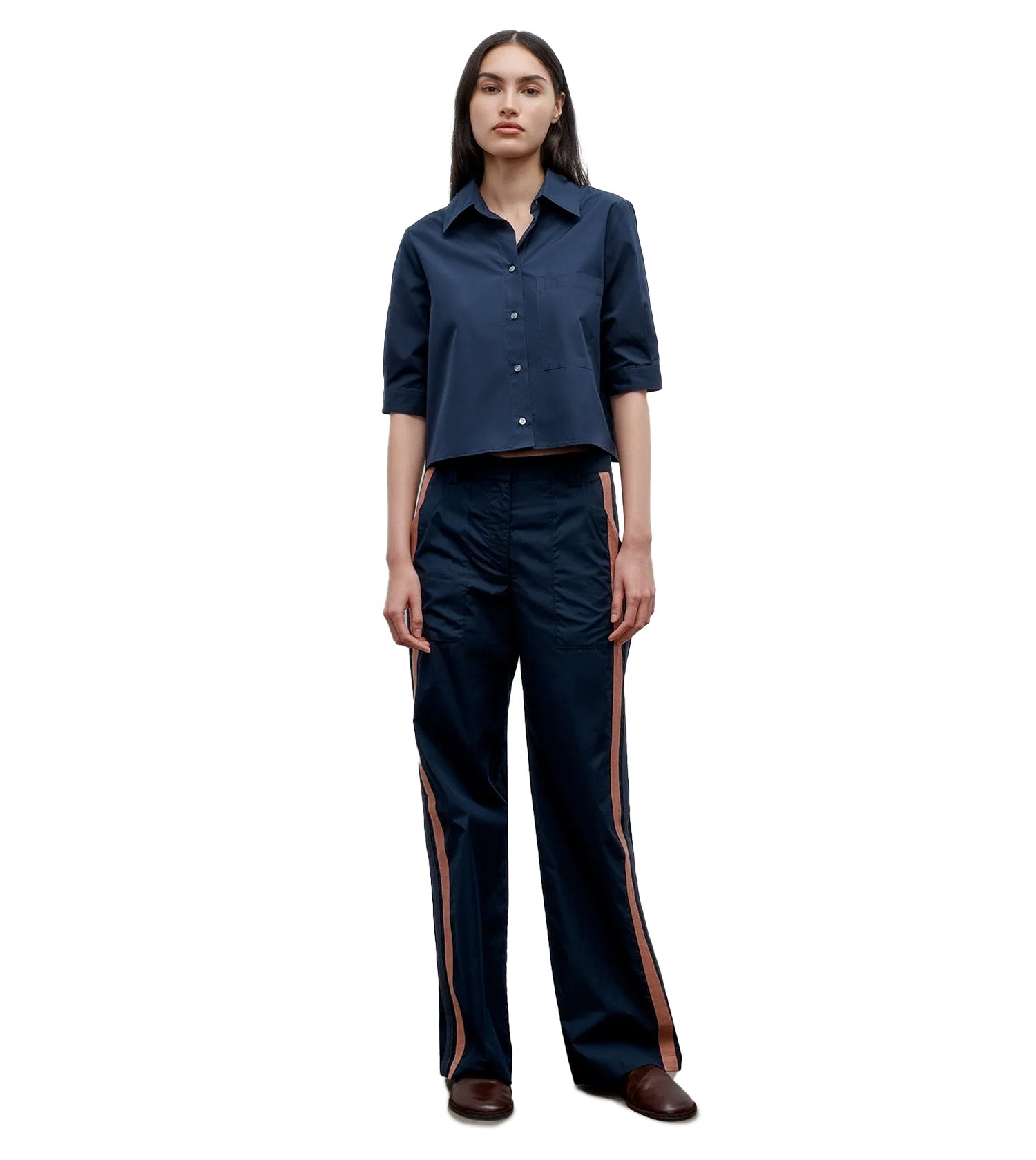 Woman wearing a navy blue shirt and pants with side stripes on a white background