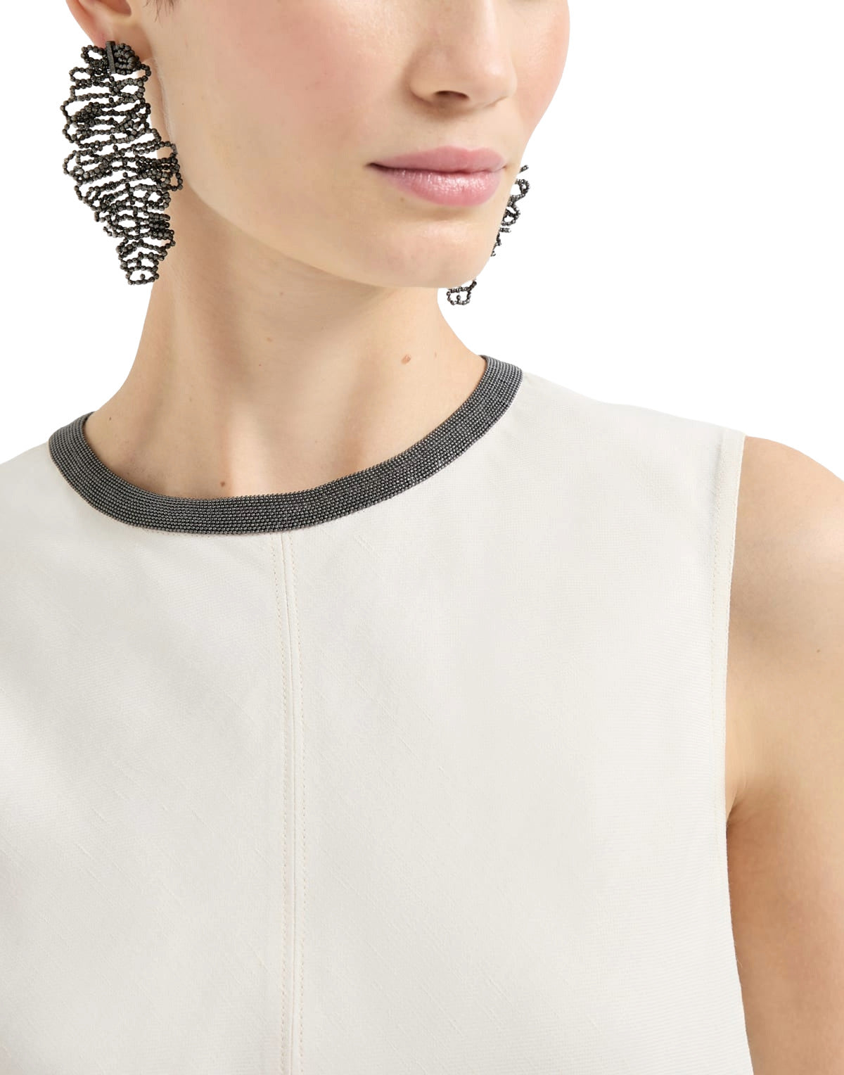 Close-up of a person wearing a white sleeveless top with a black ribbed neckline.