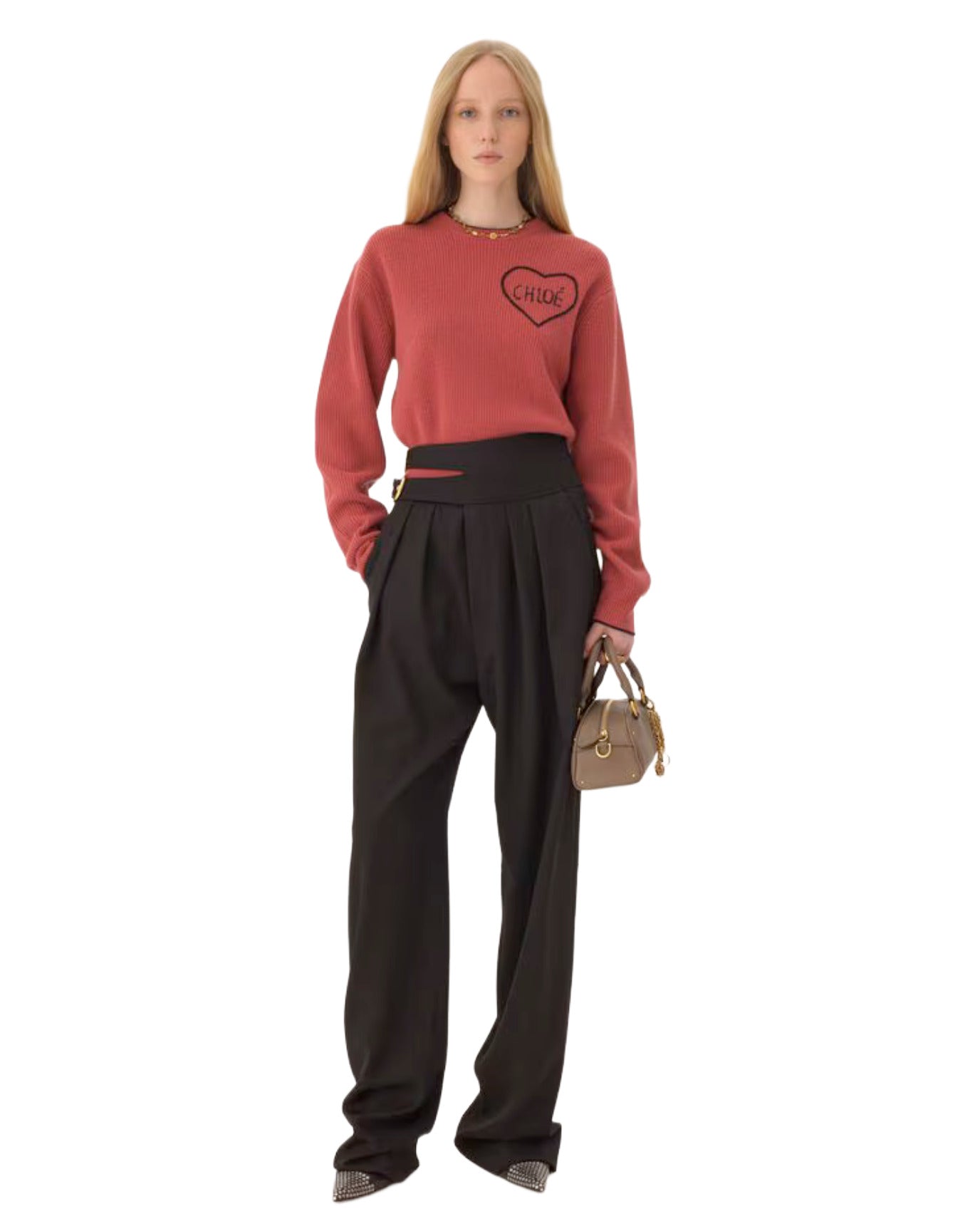 Woman wearing a red sweater with a heart design and black pants on a white background