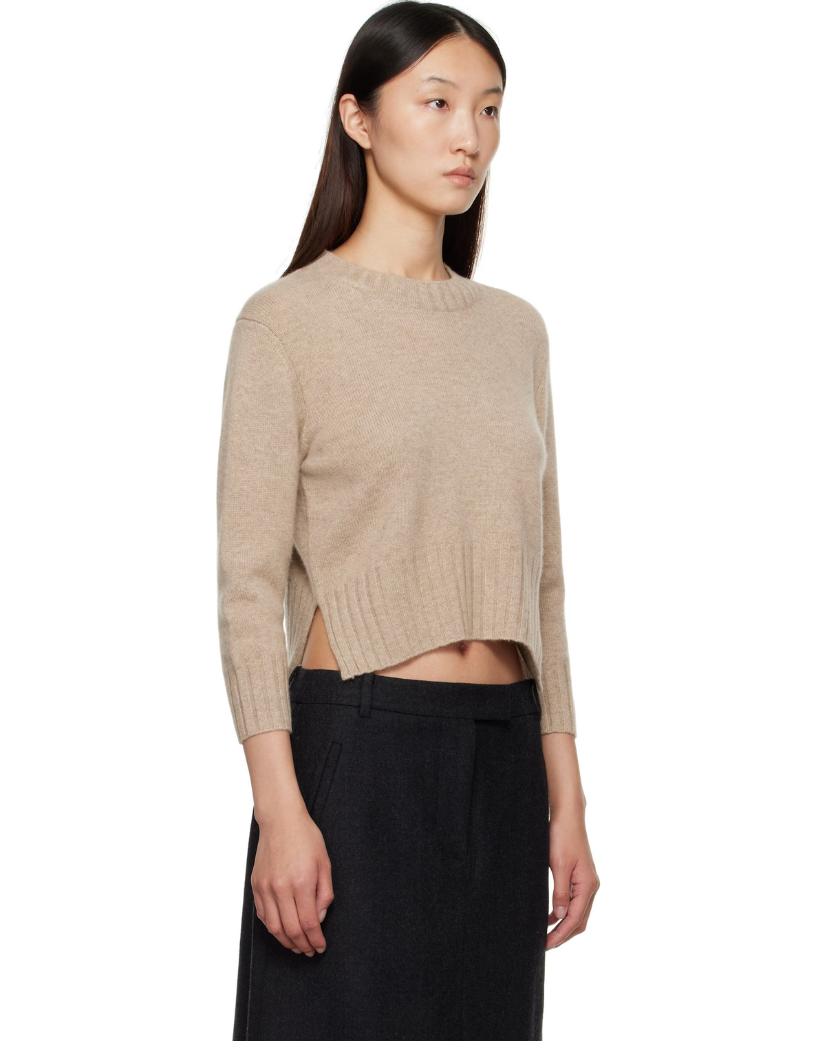 Woman wearing a beige sweater with a cutout design on a white background