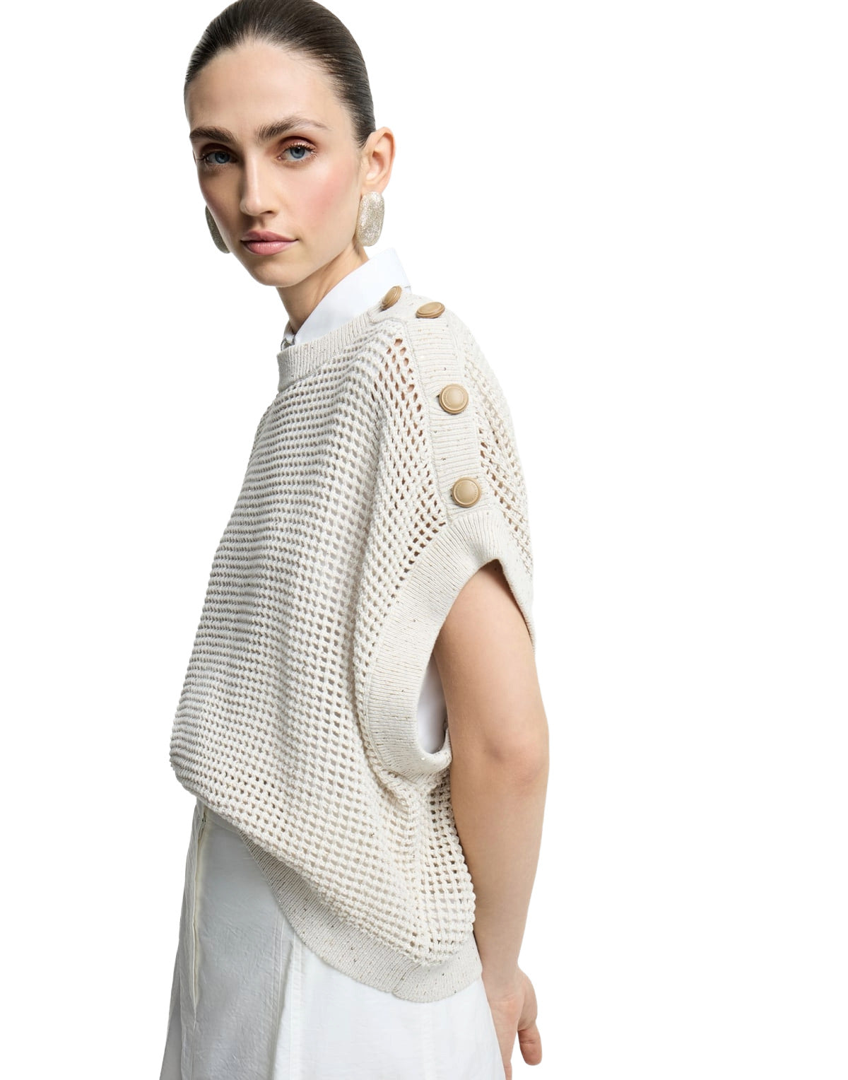 Woman wearing a beige knitted poncho with button details on a white background