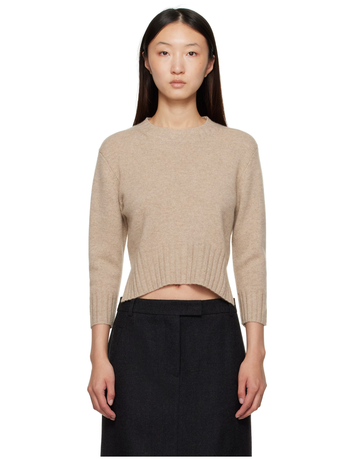 Woman wearing a beige sweater and black pants on a white background