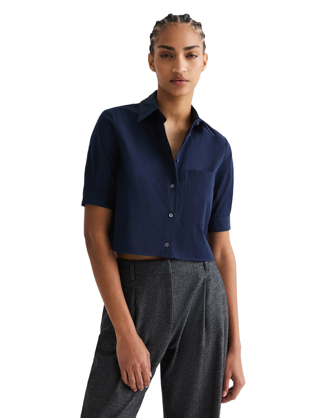 Person wearing a navy blue shirt and gray pants on a white background