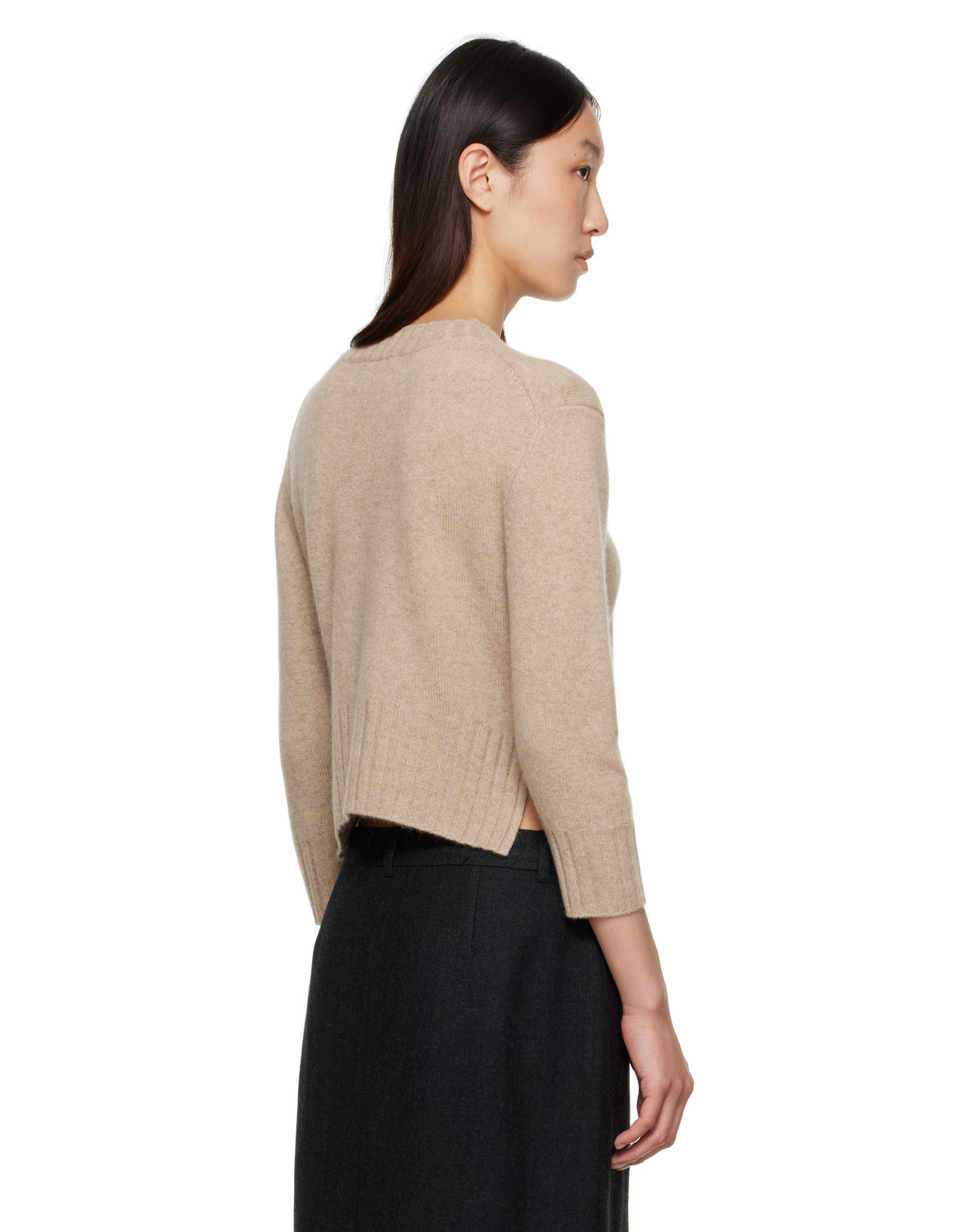 Woman wearing a beige sweater and black pants on a white background