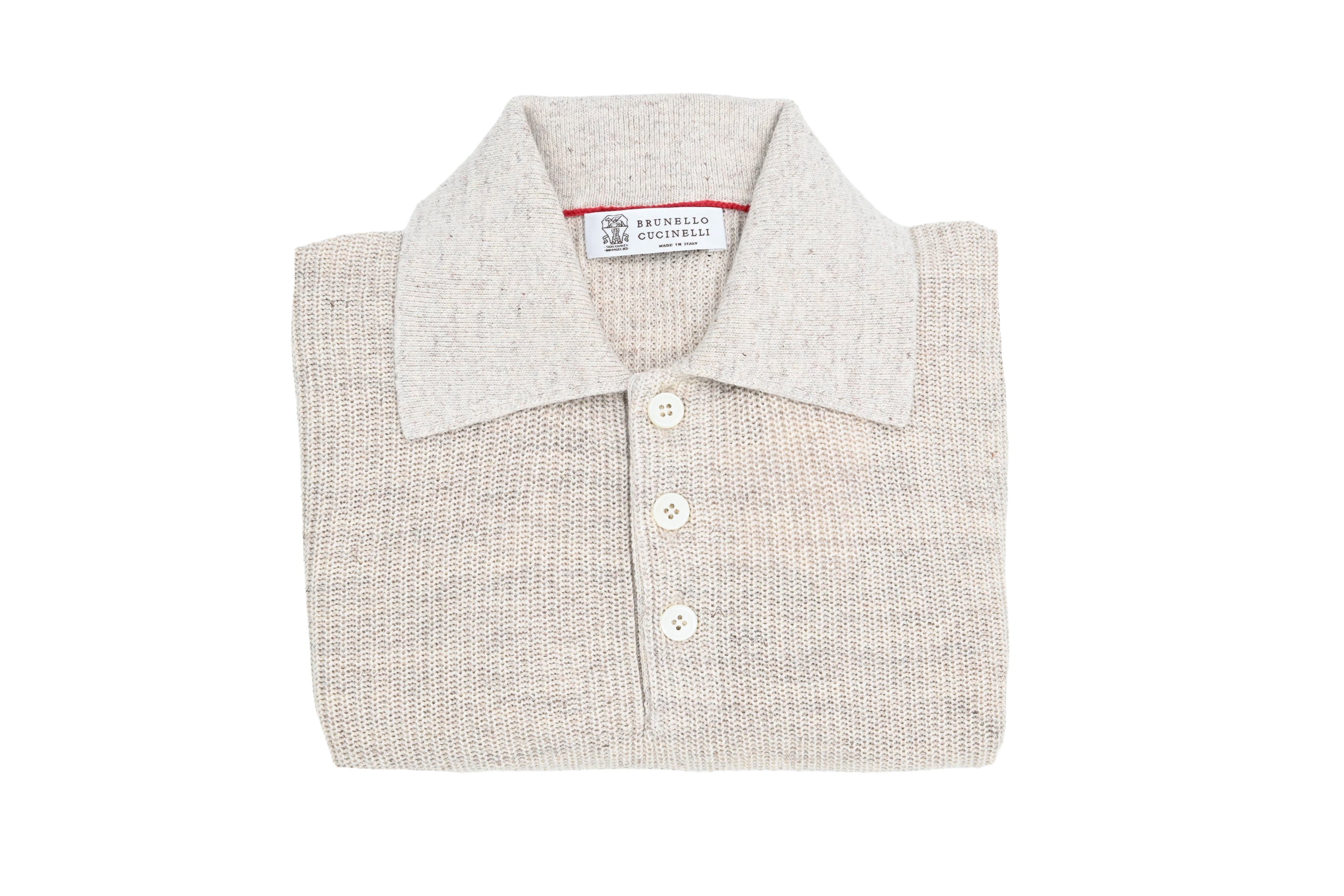 Folded light gray polo shirt with a brand label on a white background