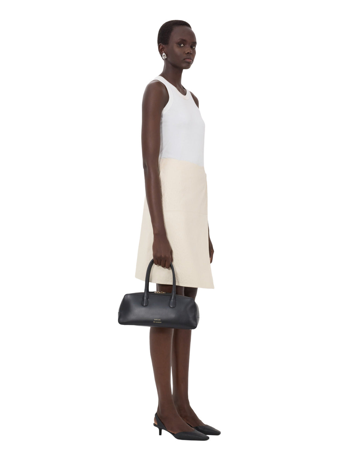 Woman wearing a two-tone dress holding a black handbag on a white background